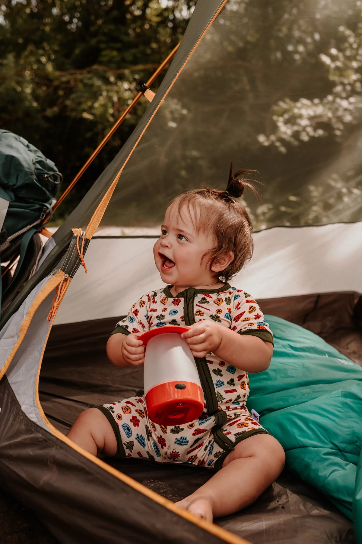 Baby wearing the Summer Camp Onesie inside the tent